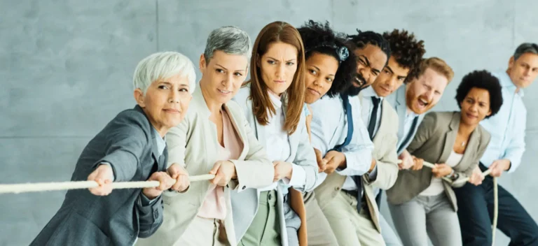 Group of diverse business professionals in formal attire participating in a team-building activity, pulling a rope together.