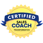 A circular gold emblem with "CERTIFIED" on a blue ribbon at the top. The center reads "SALES COACH" in bold blue and yellow text. Below, it says "TRANSFORMATION ACADEMY" in smaller black text. The outer edge of the emblem has a sunburst pattern.