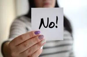 Woman holding a sign that says 'No!' empowering women to set boundaries and take control of their personal and professional lives.